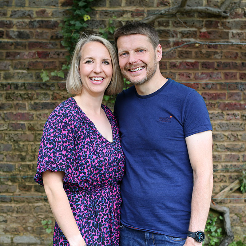 Man and woman standing together in front of a brick wall