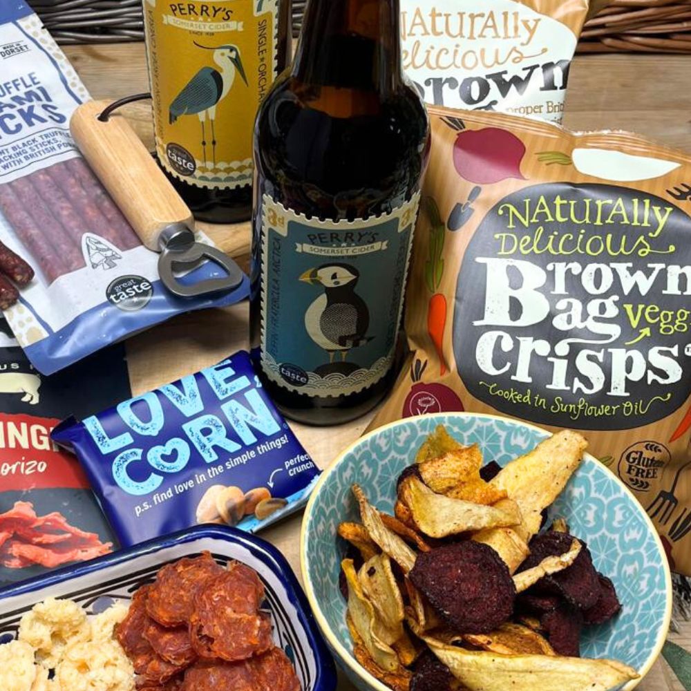 Assorted snacks including chips, beer, and other packaged goods on a wooden surface.