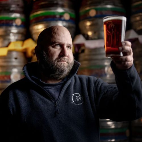 Otter Brewery employee holding up a pint of beer