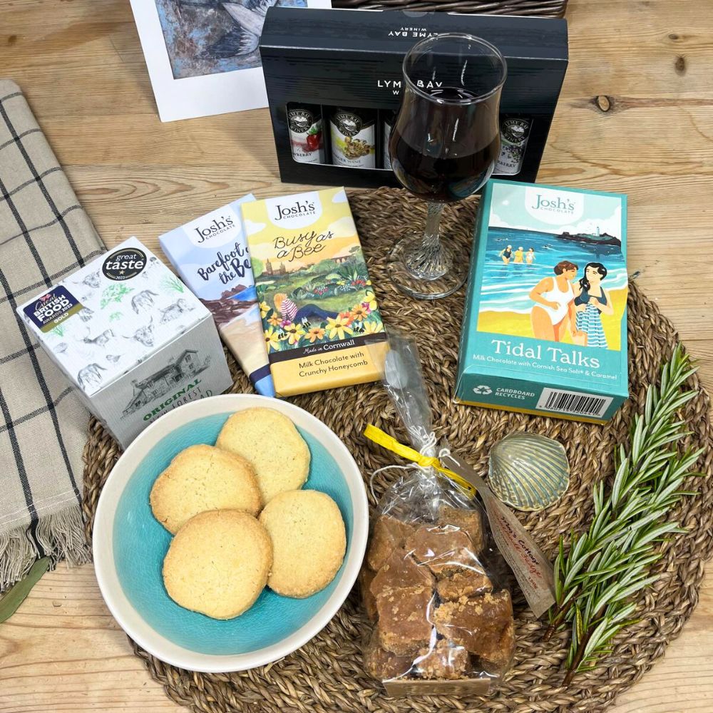 Assorted snacks and a glass of red wine on a wooden table with a woven mat.