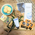 Assorted items including cookies, tea packages, and a tea towel on a wooden surface.