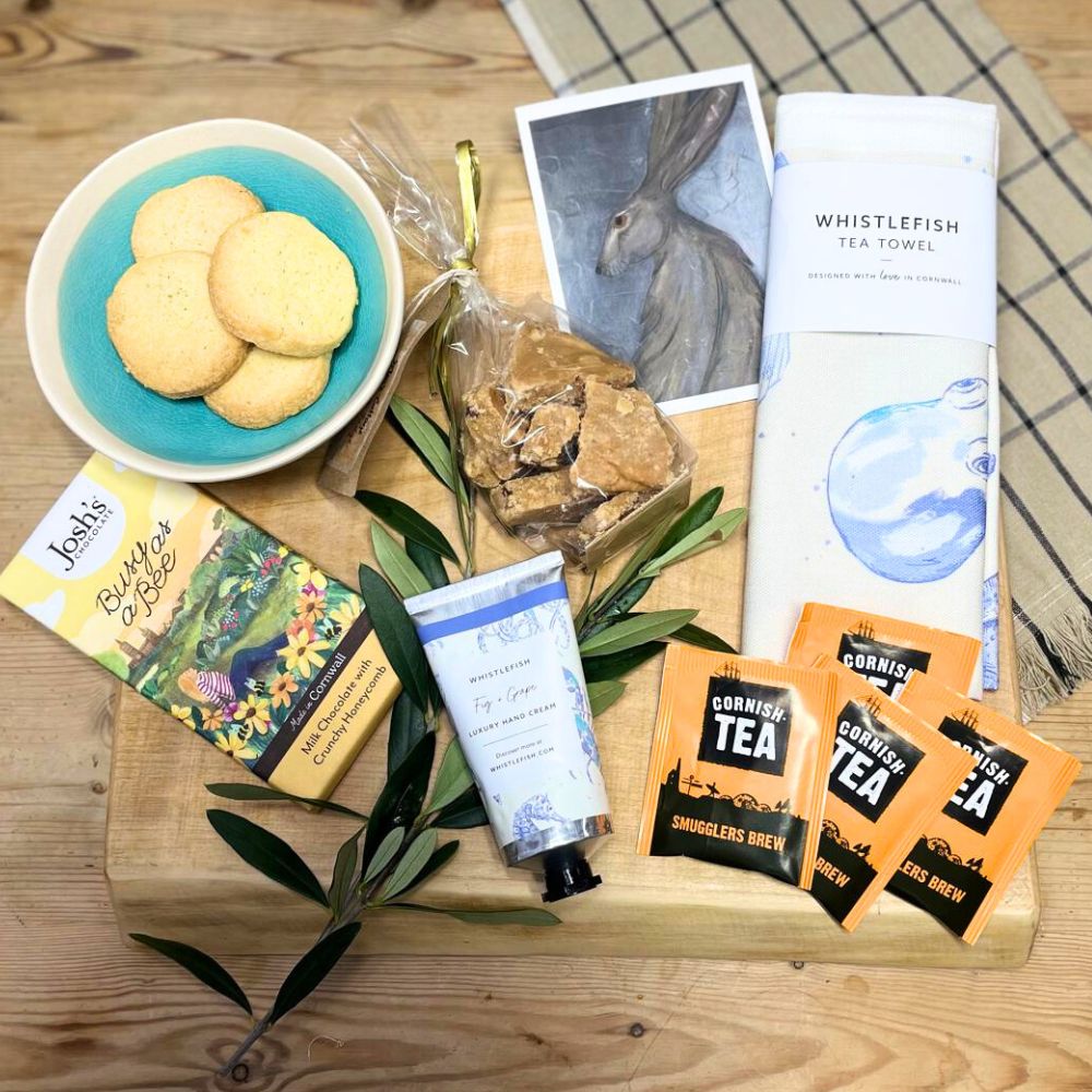 Assorted items including cookies, tea packages, and a tea towel on a wooden surface.