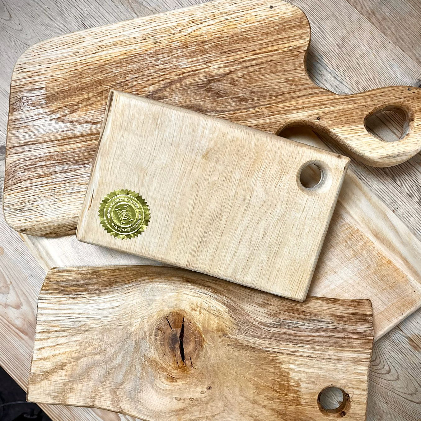 Three wooden cutting boards of different sizes on a wooden surface.